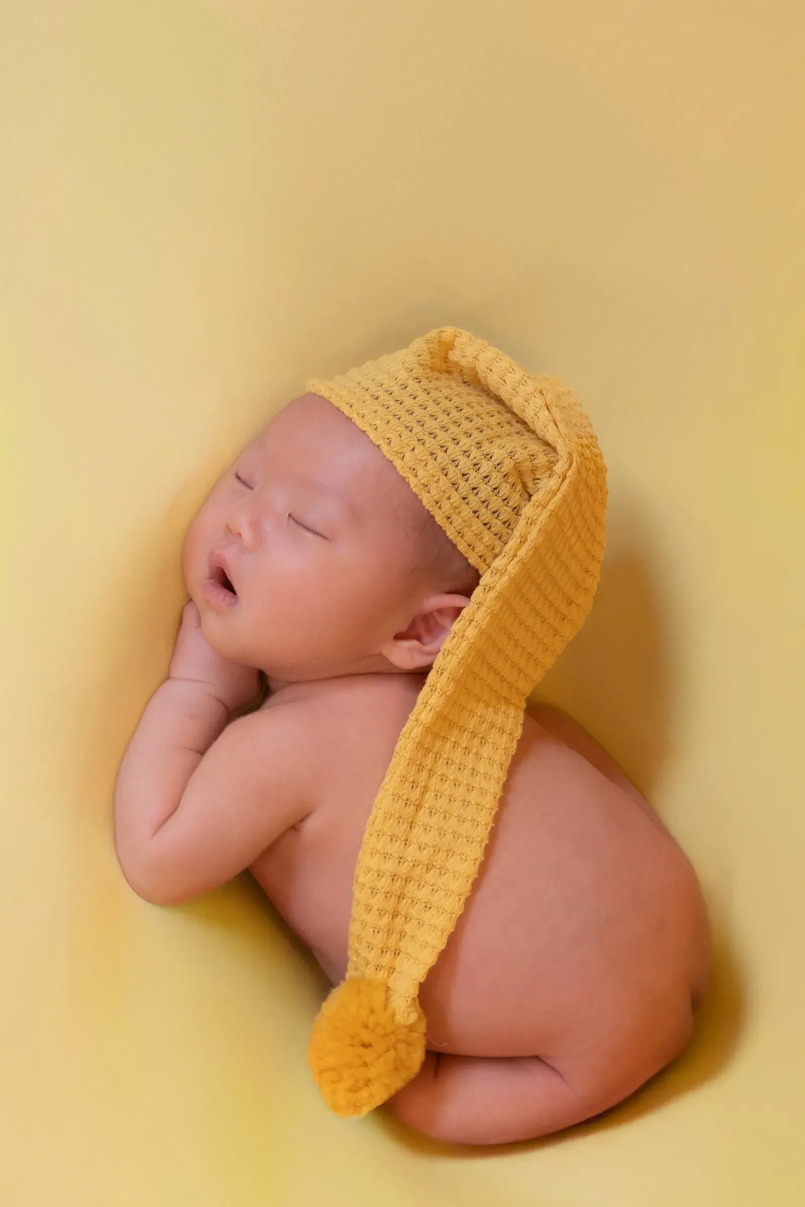 黄色いニット帽をかぶり、うつぶせで眠る赤ちゃん
