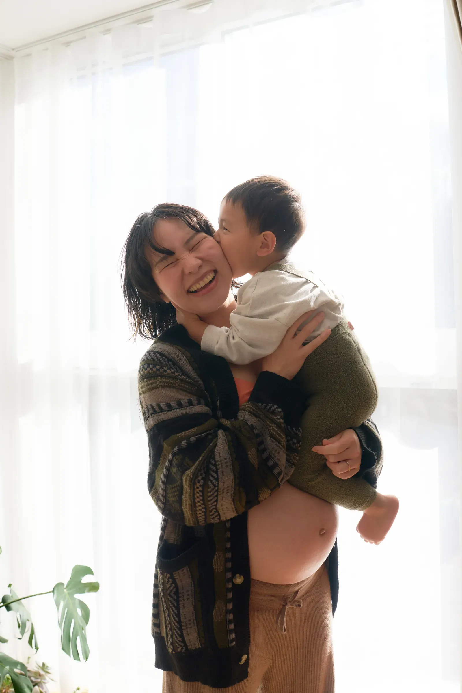 お兄ちゃんを抱っこし、頬にキスをされて笑う妊婦さん